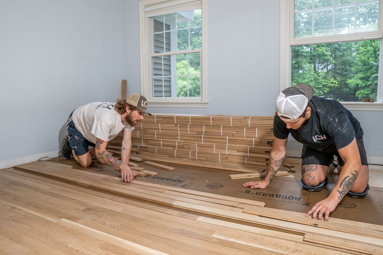 Two LCH crew members installing new hardwood flooring by hand