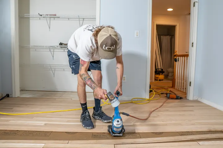 Brad Lyman of LCH nailing down new hardwood boards in an empty bedroom