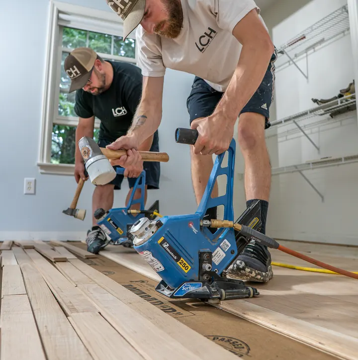 LCH installers using a flooring nailer to lay new oak hardwood in a Derry, NH home