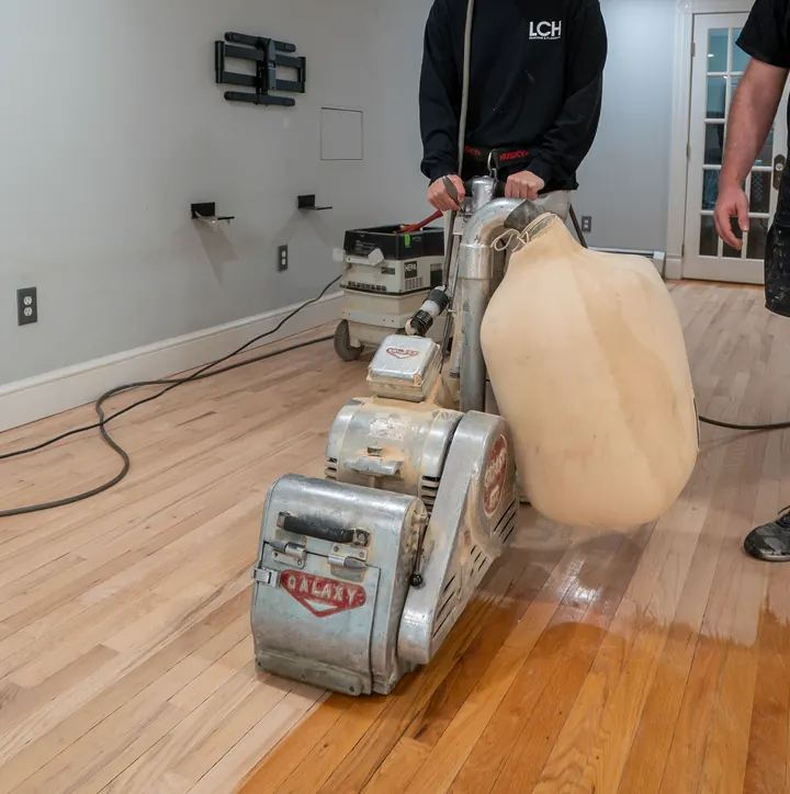 Jacob Cunningham of LCH running a drum sander across an oak floor