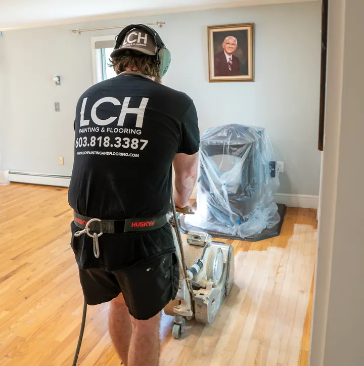 LCH crew member in an LCH shirt running a drum sander across a hardwood floor in Pelham, NH