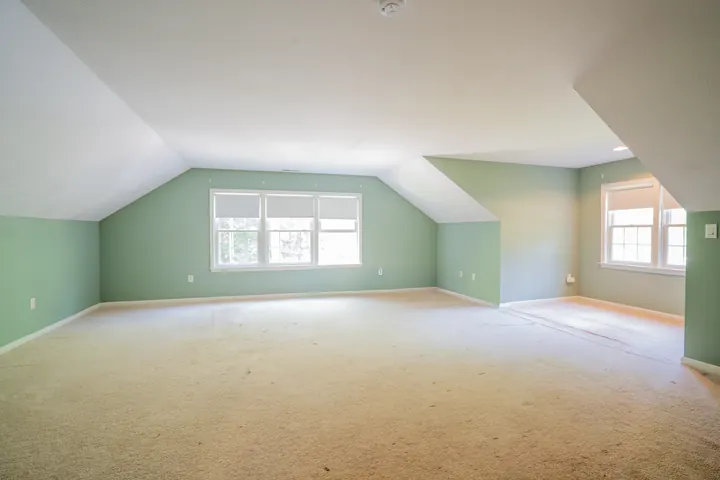 Bedford, NH bonus room with green walls and worn beige carpet before LCH refinished the hardwood underneath