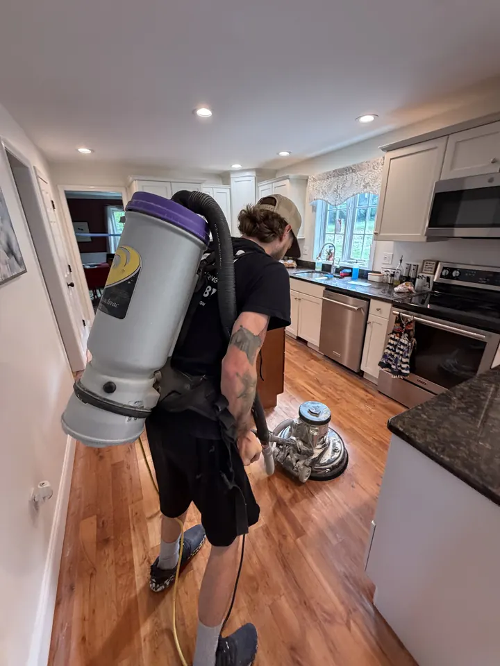 LCH crew member with a backpack vacuum while a buffer runs on a refinished kitchen floor in Hudson, NH