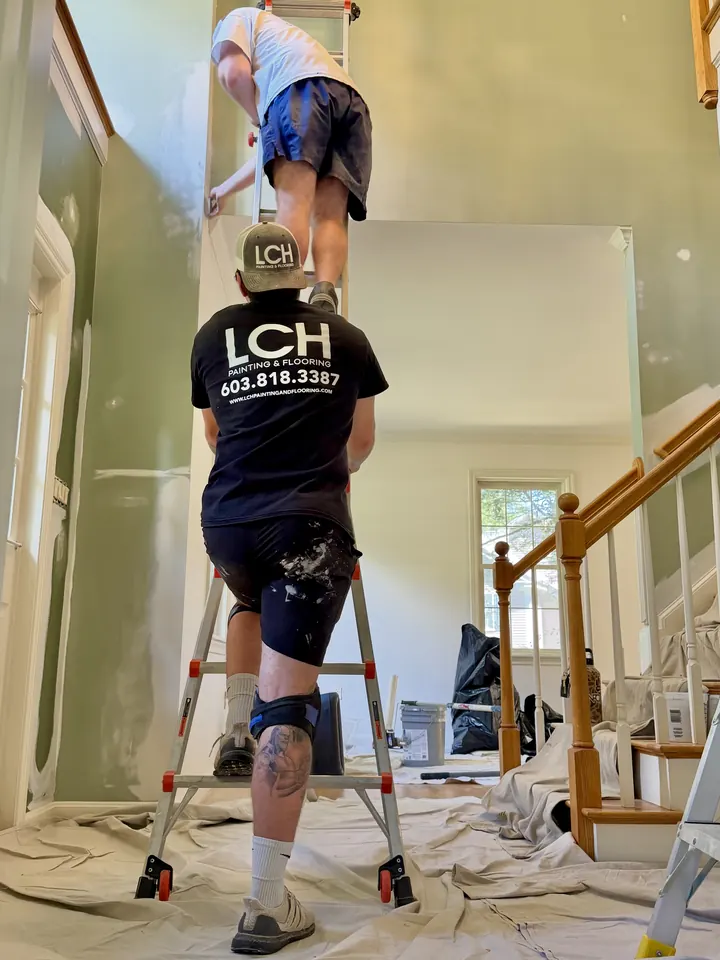 Two LCH painters working on the stairwell walls of a Salem, NH home with floors covered