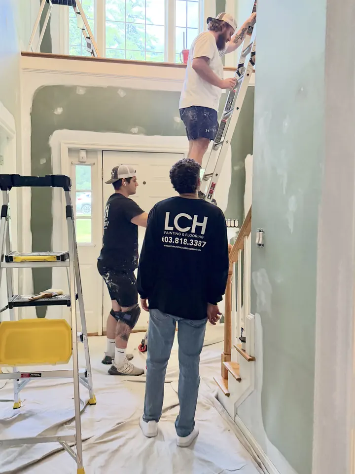 LCH painter on a ladder cutting in the upper wall of a two-story foyer in Salem, NH