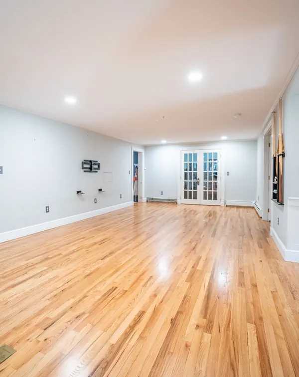 Bright open room with refinished oak floors and French doors at the end